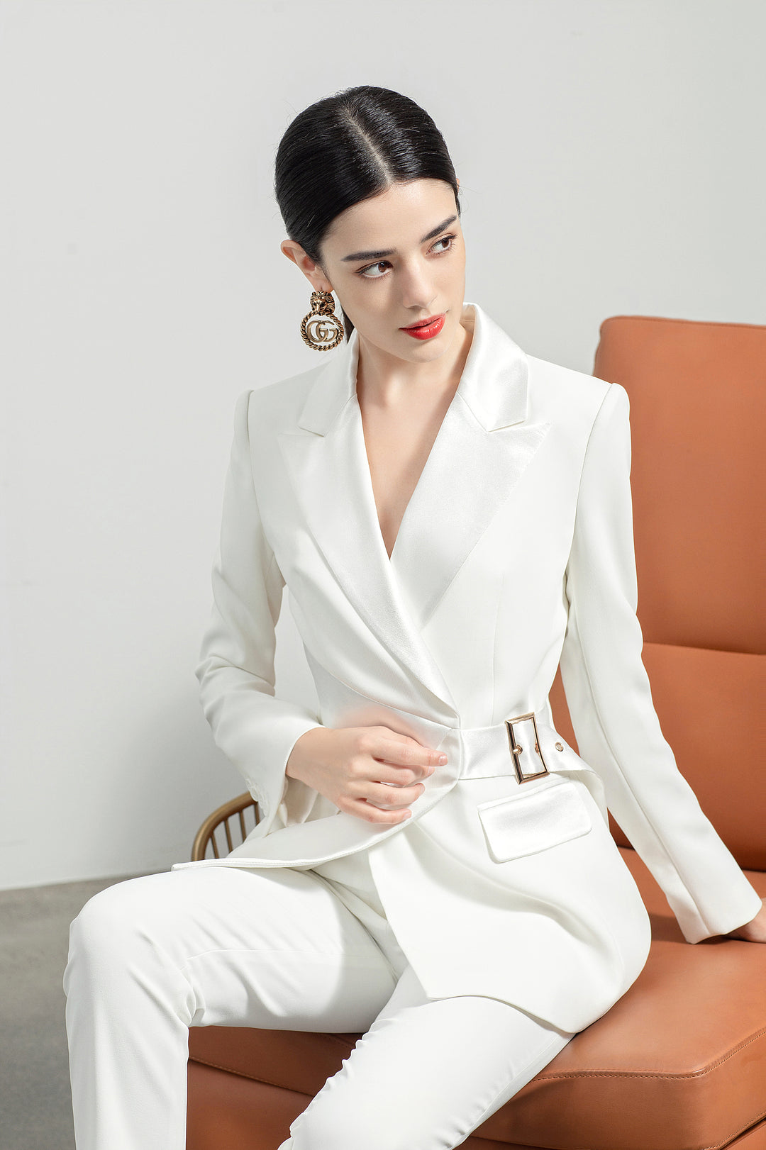 Model wearing Meliora's white Alabaster trouser suit with sitting pose