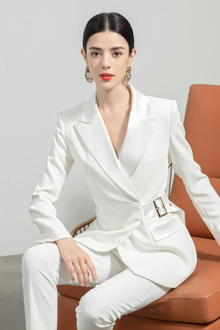 Model wearing Meliora's white Alabaster trouser suit with sitting pose